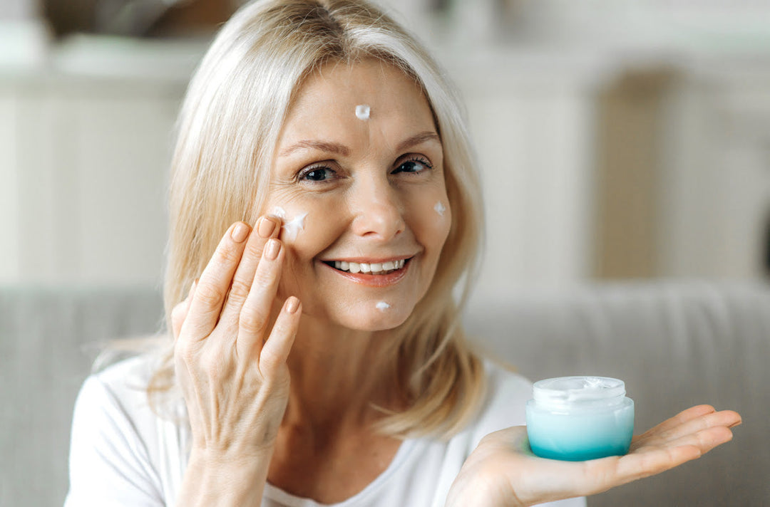 Beautiful older lady applying moisturizer with a smile