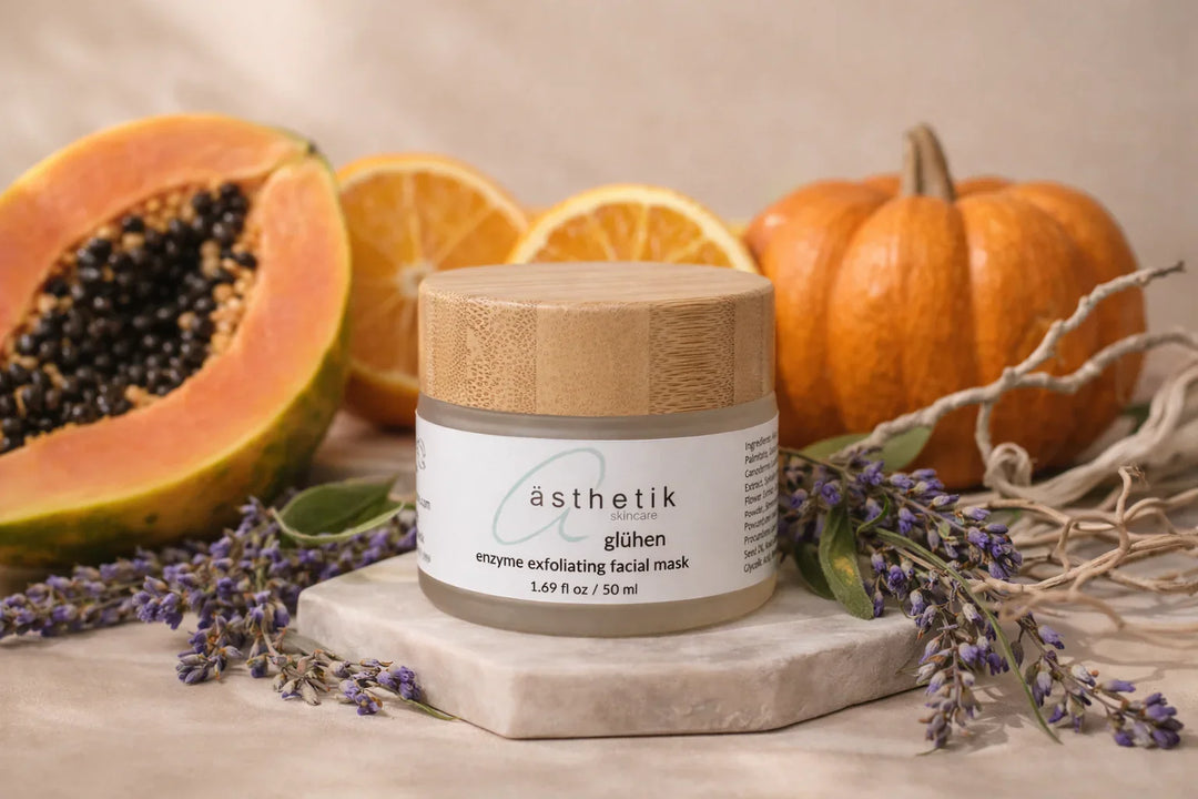 ästhetik skincare enzyme exfoliating mask glühen sitting on a tan backdrop with a papaya, oranges, pumpkin and lavender arranged around it