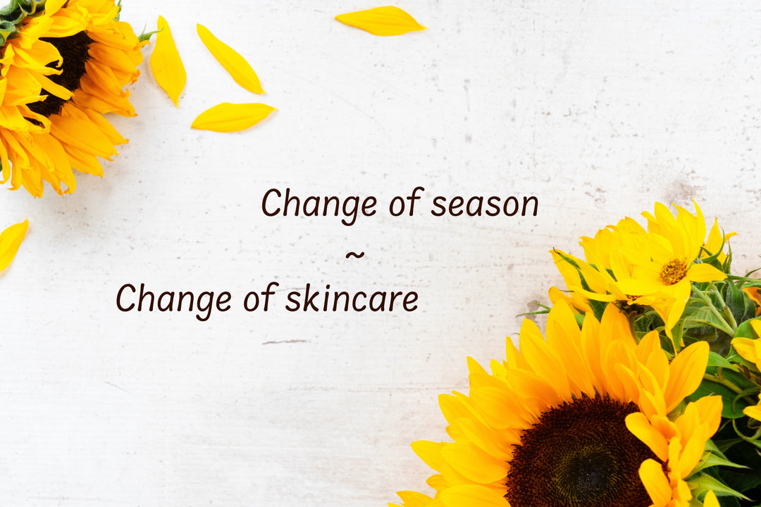 Change of season ~ change of skincare written out on a white wooden background frame in opposite corners with sunflowers