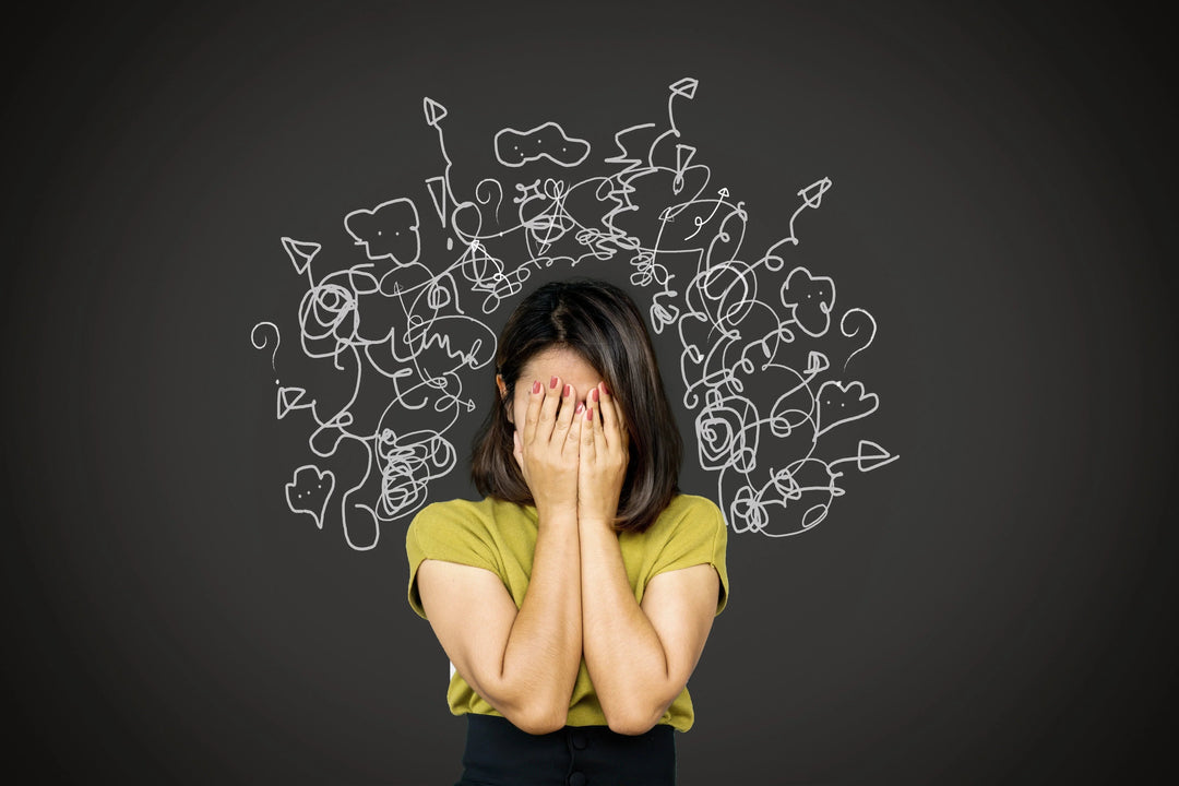 Stressed woman covering face with hands, abstract white doodles behind representing mental clutter