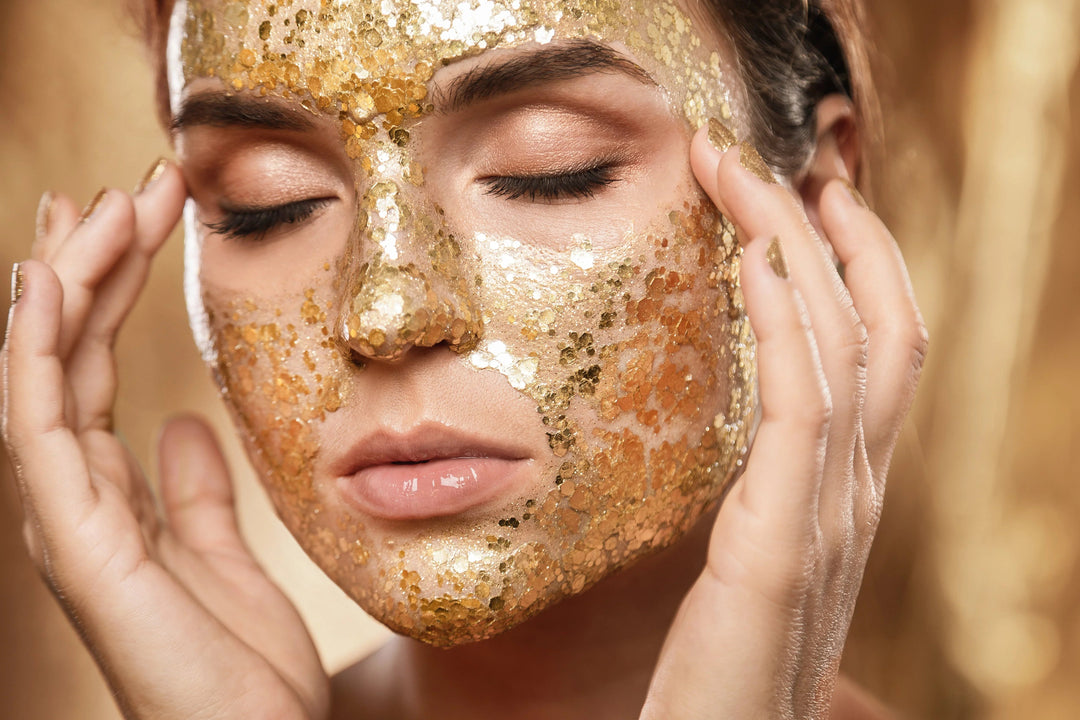 Close-up of woman with eyes closed applying gold glitter facial mask, glowing skin, skincare beauty