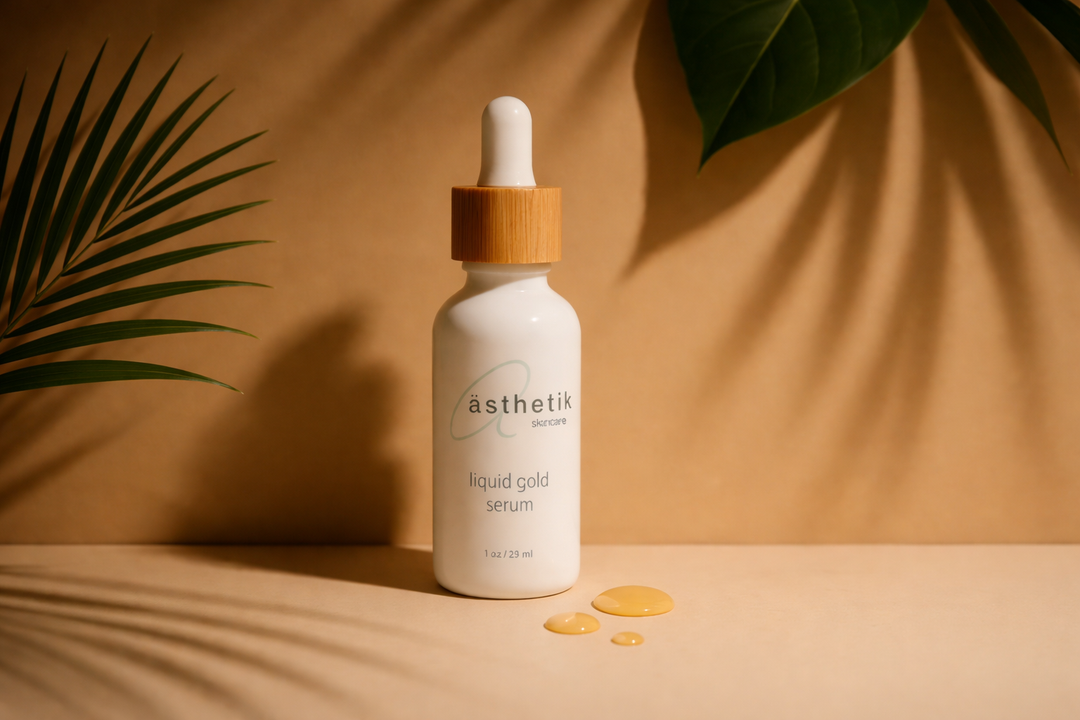Liquid Gold Serum by ästhetik skincare displayed on a warm neutral background with botanical shadows and golden serum drops.