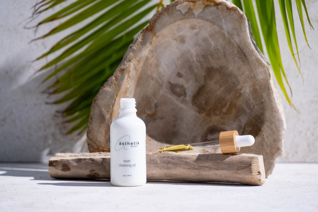 ästhetik skincare reset cleansing oil displayed with a decorative rock and palm frond