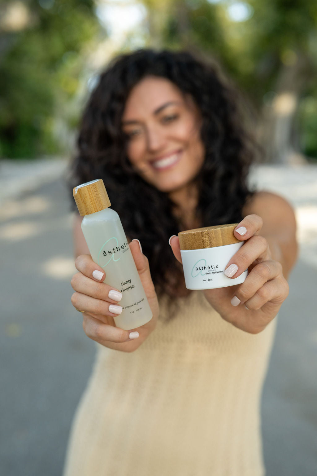 Beautiful young woman blurred in the background holding out ästhetik skincare clarity cleanser and moisturizer