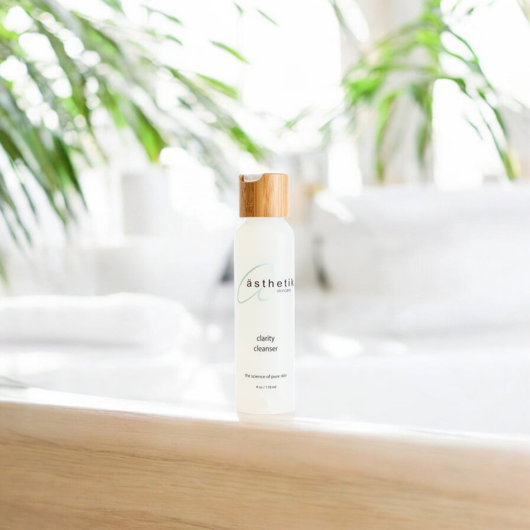 Asthetik Skincare Clarity Cleanser on a wooden vanity with a white counter and palms in the background