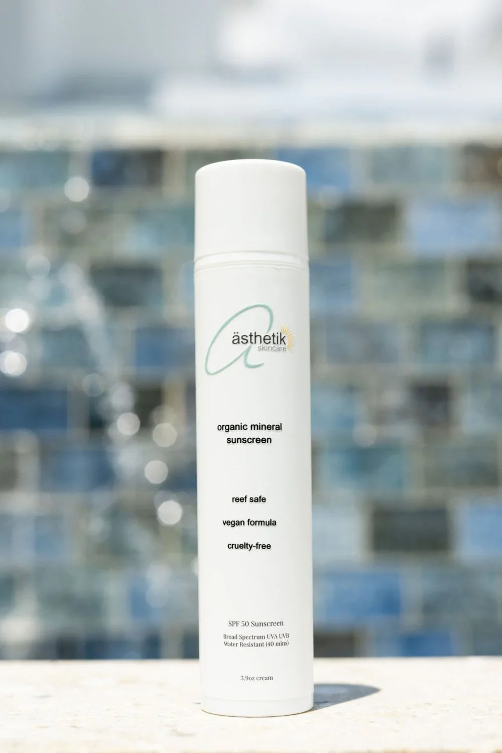 ästhetik skincare organic mineral SPF 50 sunscreen bottle against a blue tiled background