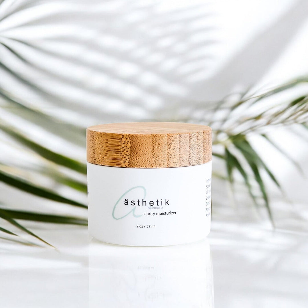 ästhetik skincare clarity moisturizer with a white background and palm leaves and shadows behind it