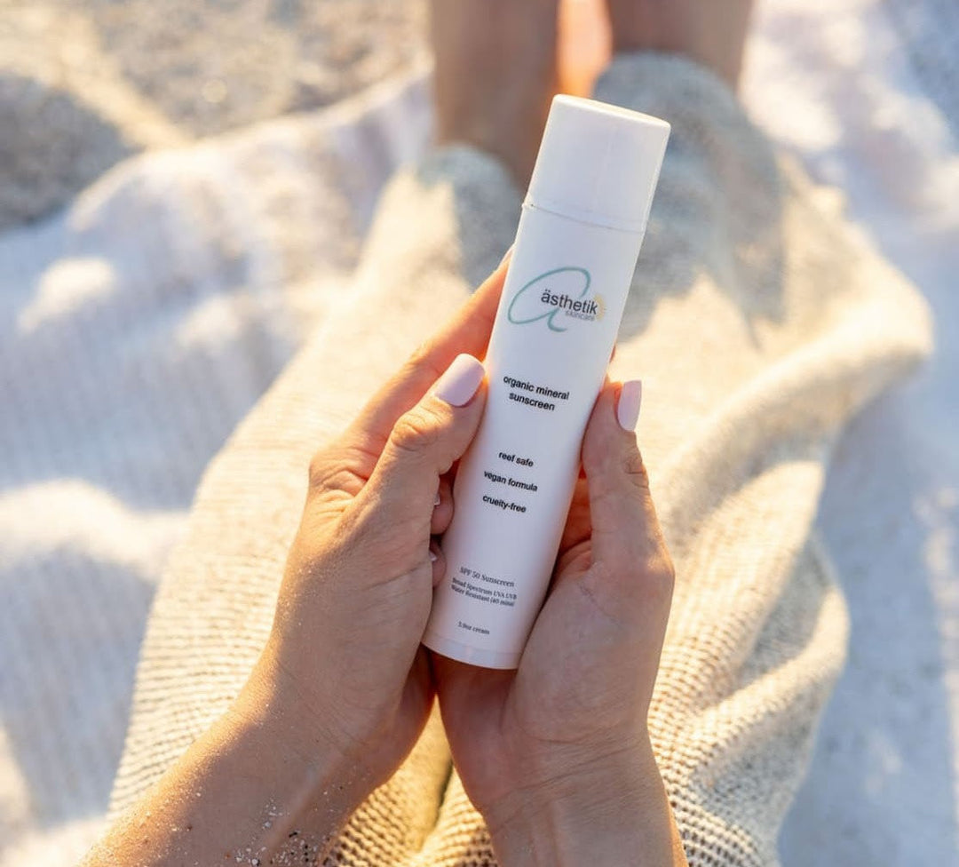 ästhetik skincare organic tinted mineral sunscreen SPF50 being held at the beach