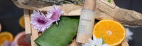 A bottle of aloe vera and oranges on top of a wooden box.