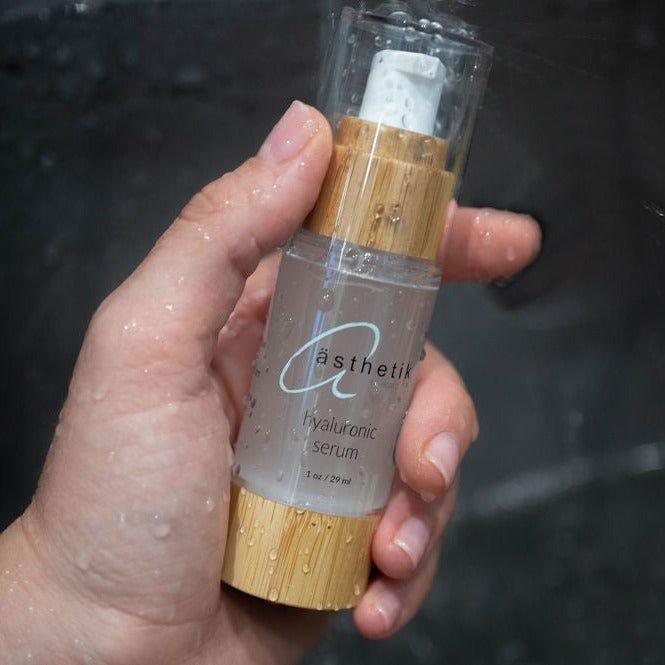 Hyaluronic serum from ästhetik skincare in a hand-held glass bottle with bamboo cap