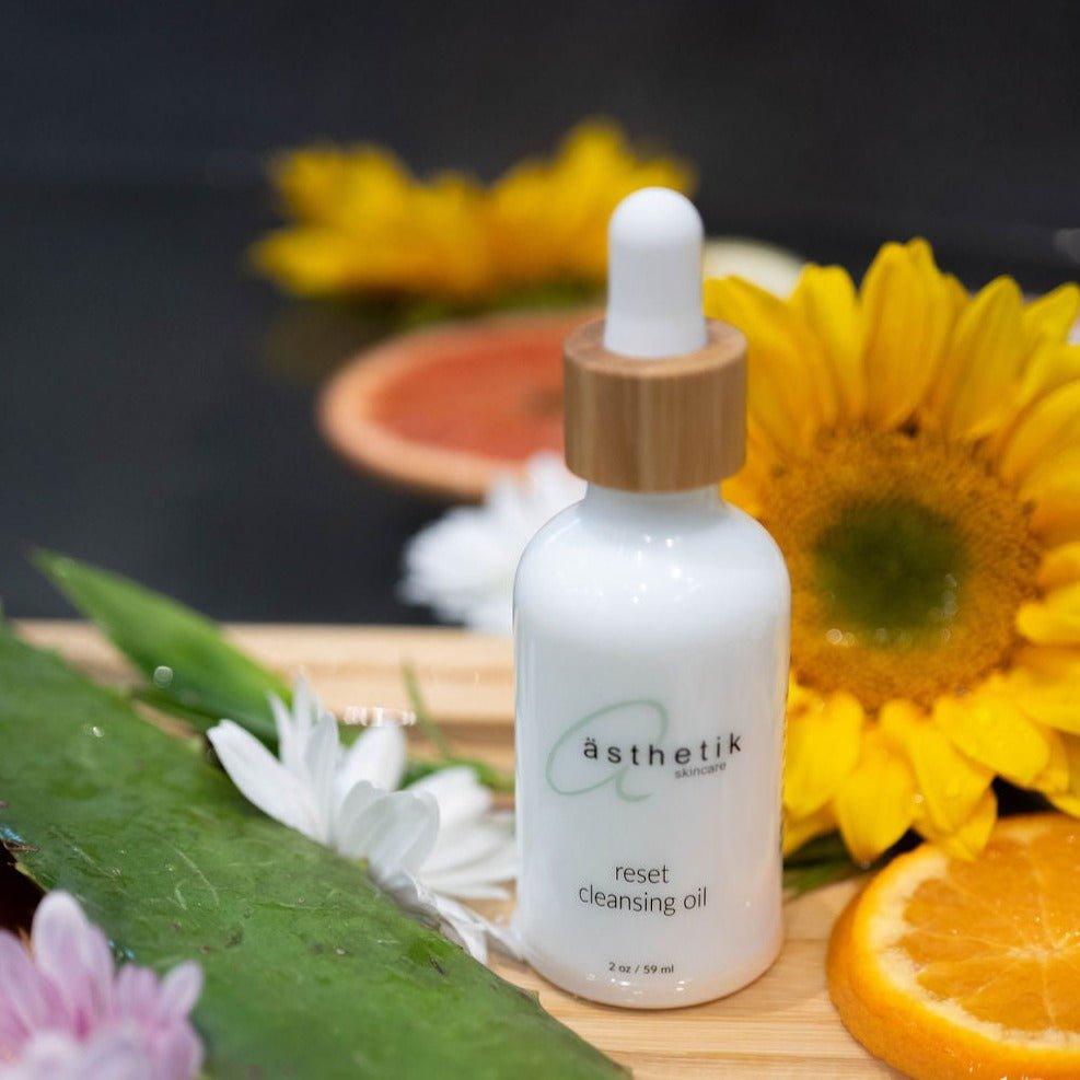 Botanical-rich reset cleansing oil from ästhetik skincare amidst fresh flowers and citrus slices on wooden board