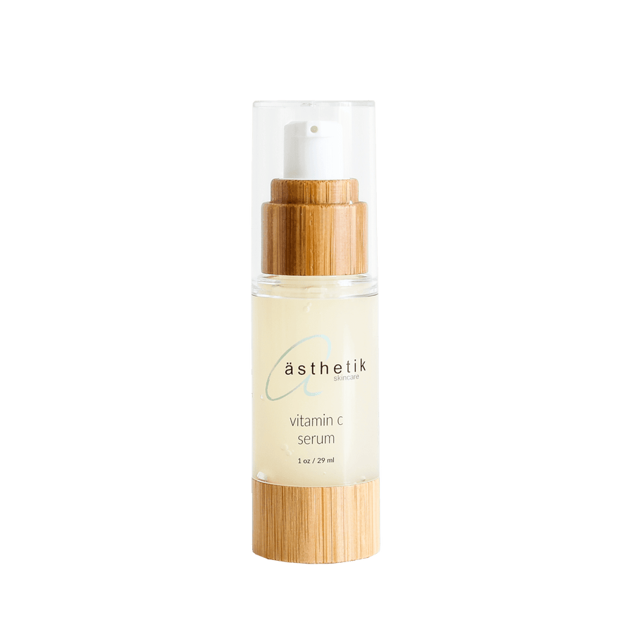 Vitamin C serum by ästhetik skincare, in a clear glass bottle with a bamboo cap, showcased on a vibrant green background.
